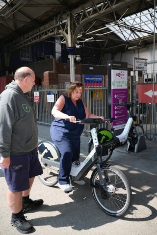 An image of HITRANS staff supporting a member of the public on one of the HiBikes
