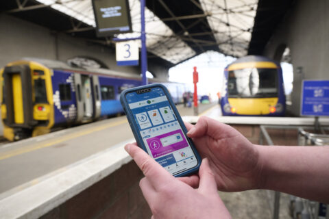 Mobile phone being held up with trains in the background