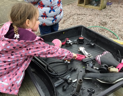 child playing with a selection of bike parts