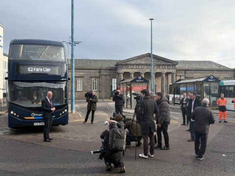 Image of Inverenss Bus Station with the First Minister John Swinney beside a bus promoting the new £2 fare cap pilot