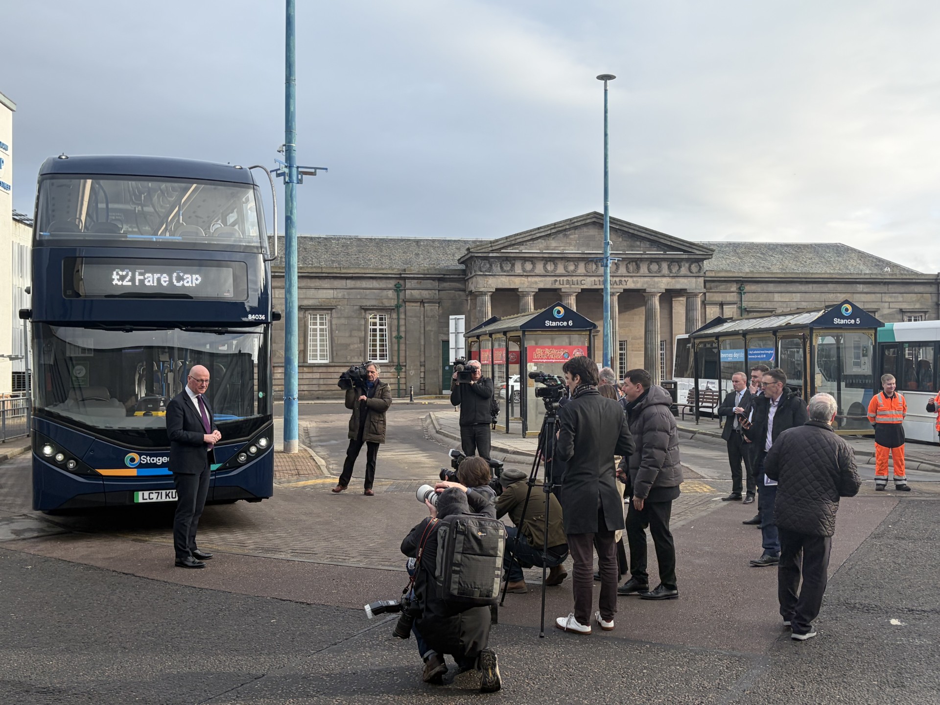 Image of Inverenss Bus Station with the First Minister John Swinney beside a bus promoting the new £2 fare cap pilot