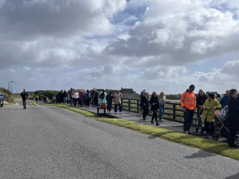 A line of people walking along a newly constructed path in South Uist