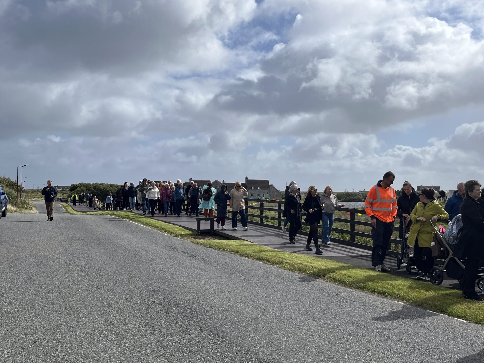 A line of people walking along a newly constructed path in South Uist